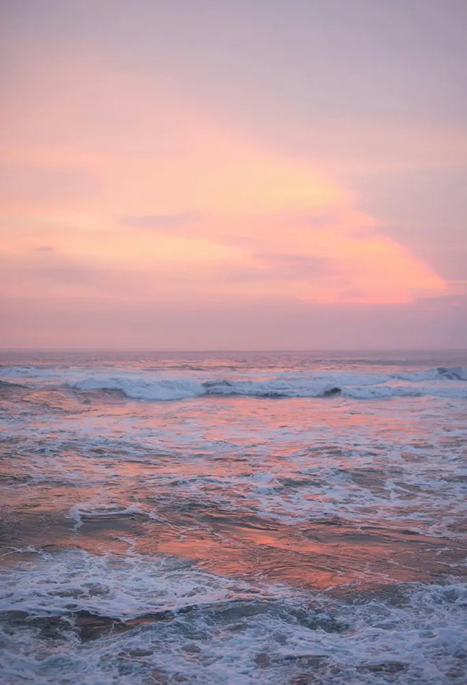 A pink and apricot sunset over a gentle sea