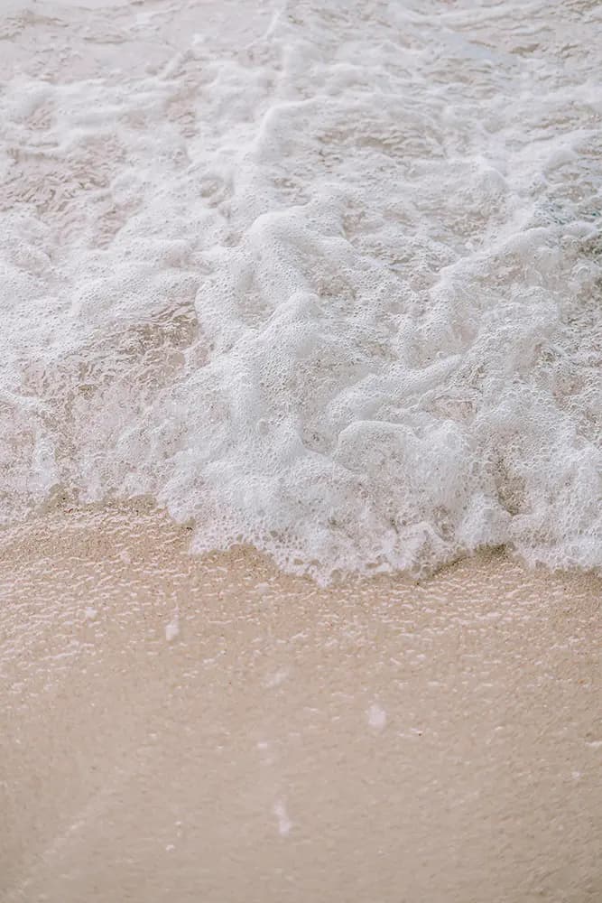 Sea foam washing gently over soft sand
